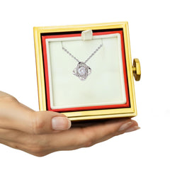 A luxury rotating gift box revealing a love knot necklace beneath a preserved eternal rose that never fades.